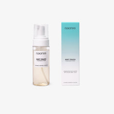 Naeriss Soft Touch Cleansing Foam in a transparent pump bottle with light beige liquid, shown next to a turquoise-to-white gradient box labeled with fermented rice water, aloe vera, and CICA. A gentle foaming face wash formulated to cleanse, soothe, and refresh sensitive or reactive skin.