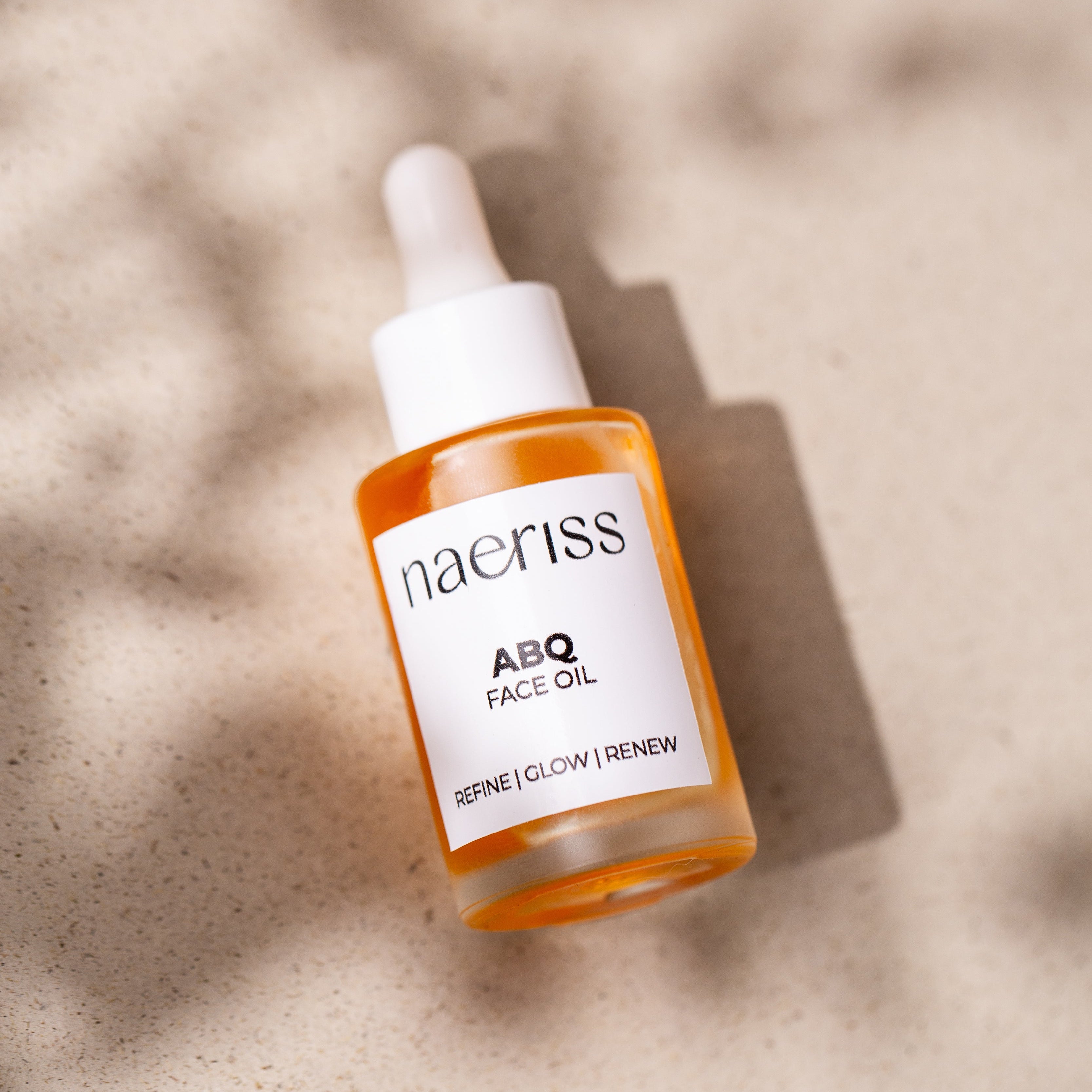 Naeriss ABQ Face Oil bottle on a textured beige background